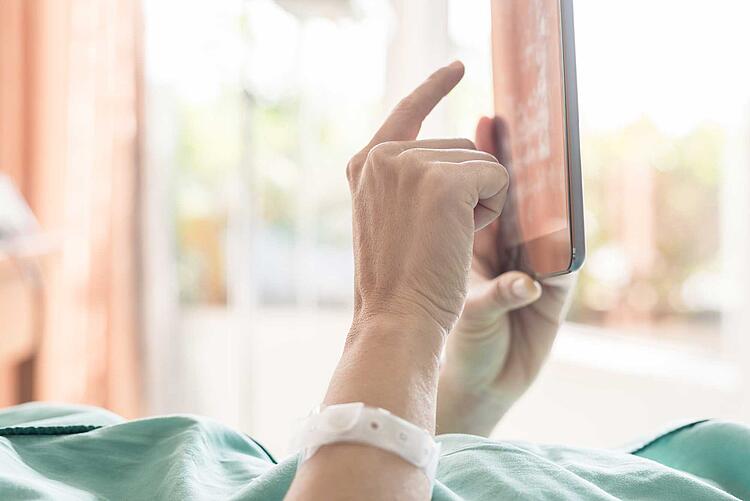 Patientin benutzt im Krankenhausbett ein Tablet