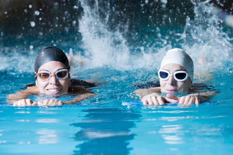 Zwei Frauen schwimmen gemeinsam im Schwimmbad