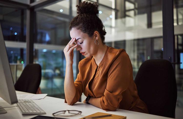 Chronischer Stress: Frau arbeitet noch spät abends im Büro