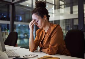 Chronischer Stress: Frau arbeitet noch spät abends im Büro