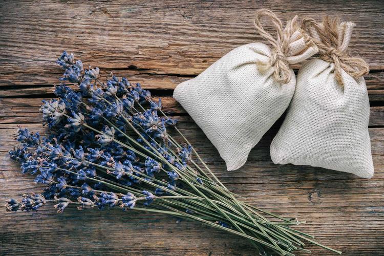 Zwei Lavendelsäckchen und ein Strauß Lavendelblüten auf einem Holztisch