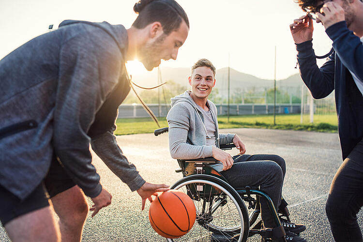 Junger Mann im Rollstuhl spielt Basketball.