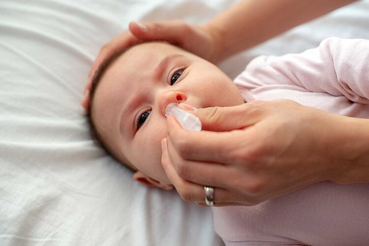 Mutter gibt einem Baby Nasentropfen