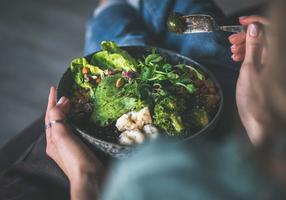 Frau isst eine Bowl mit Salat