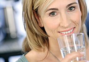 Eine Frau mit einem Glas Wasser in der Hand.