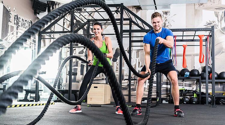 Mann und Frau im Fitnessstudio trainieren mit dem Fitness-Seil Battle Rope