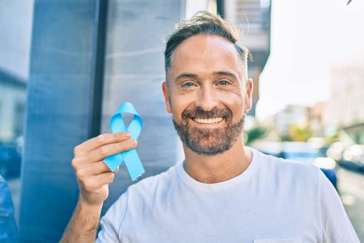 Mann hält eine blaue Schleife in der Hand, die Aufmerksamkeit für die Krankheit Prostatakrebs erzeugen soll