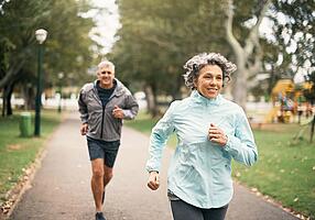 Eine Frau und ein Mann beim Joggen im Park.