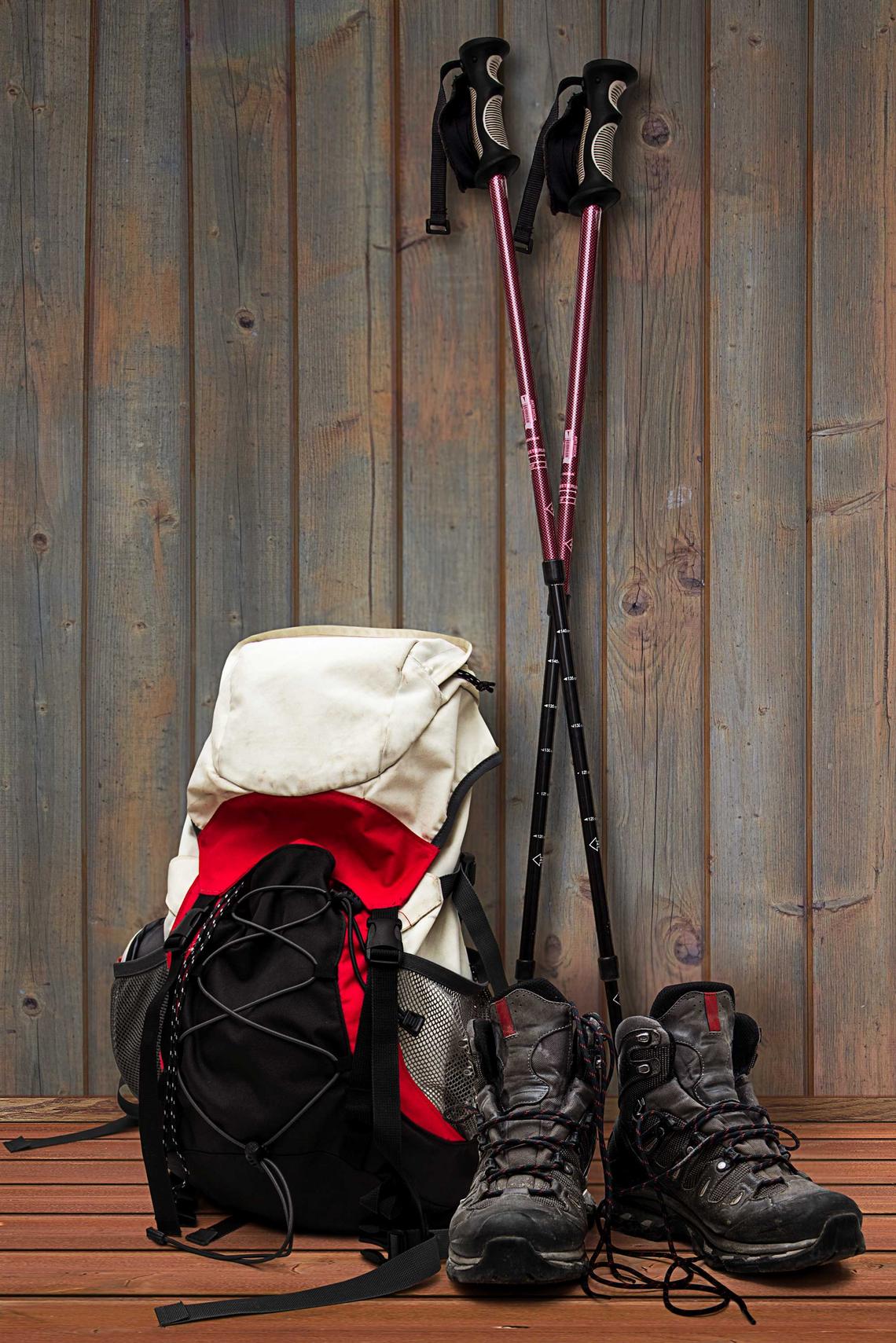 Bildnachweis: © stock.adobe.com / triskelant Wanderrucksck, Wanderschuhe und Wanderstöcke lehnen an einer Holzwand