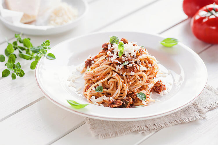 Spaghetti Bolognese mit Parmesankäse in einem Teller.