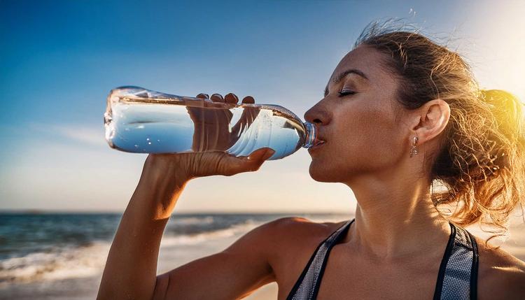 Bildnachweis: © stock.adobe.com / intricateflow Frau trinkt bei warmem Wetter Wasser aus der Flasche