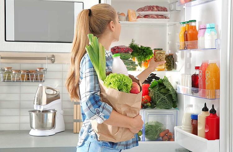 Frau räumt Einkauf in den Kühlschrank