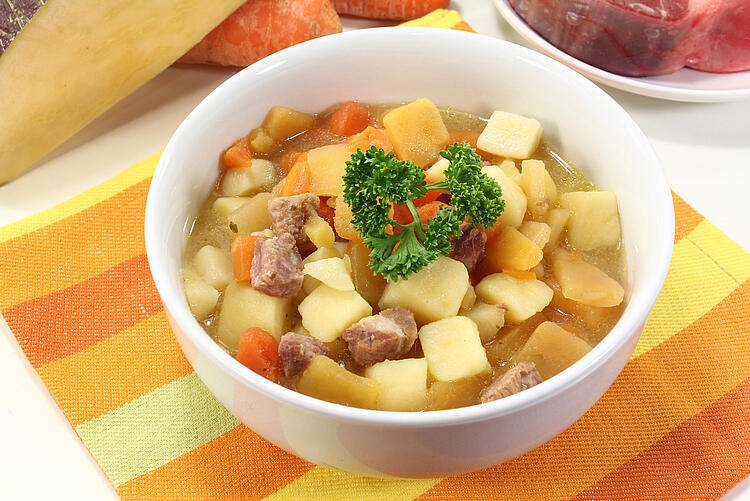 Steckrübeneintopf mit Möhren und Kartoffeln in einer Suppenschüssel mit Petersilie garniert. 