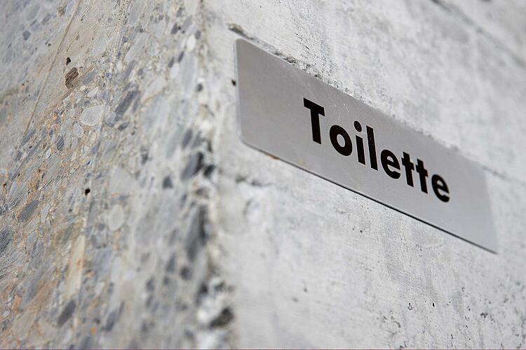 Schild an einer Hauswand mit der Beschriftung Toilette.