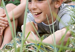 Zwei Kinder auf einer Decke im Gras.