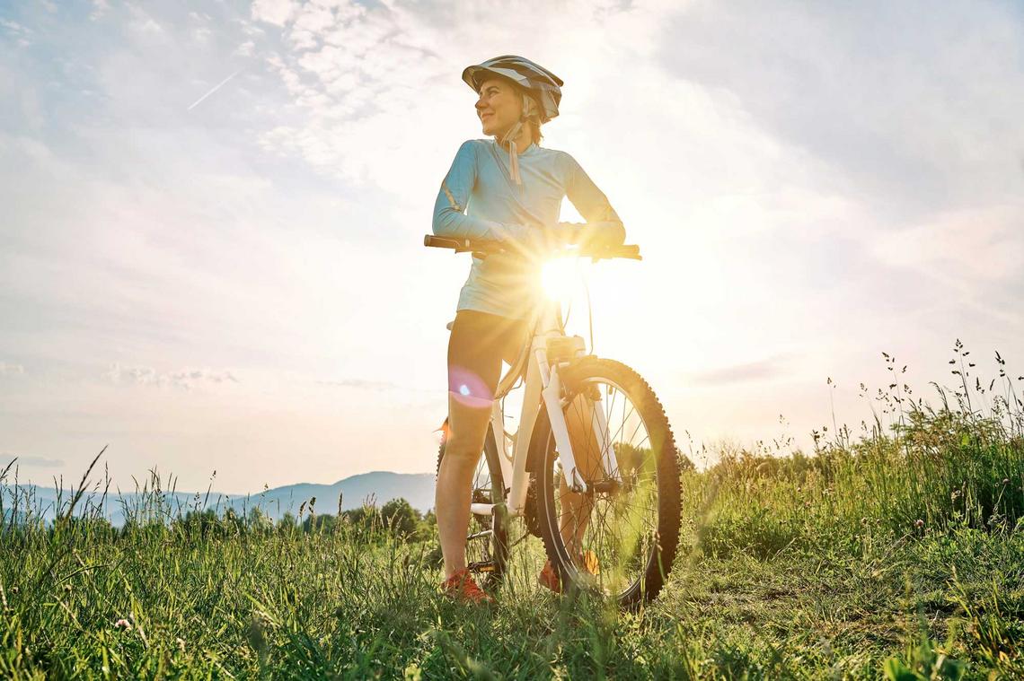 Frau genießt beim Radfahren die Aussicht bei Sonnenuntergang