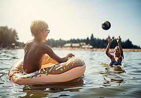 Mutter und Sohn spielen Ball im See