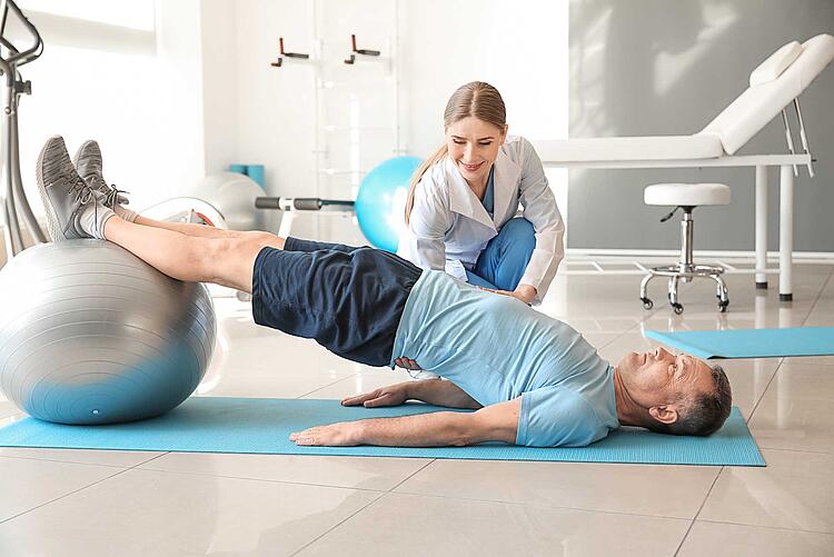 Physiotherapeutin macht Übungen mit einem Patienten