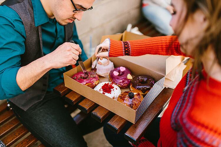 Ein Paar teilt sich bunt verzierte Donuts aus einer Pappschachtel.