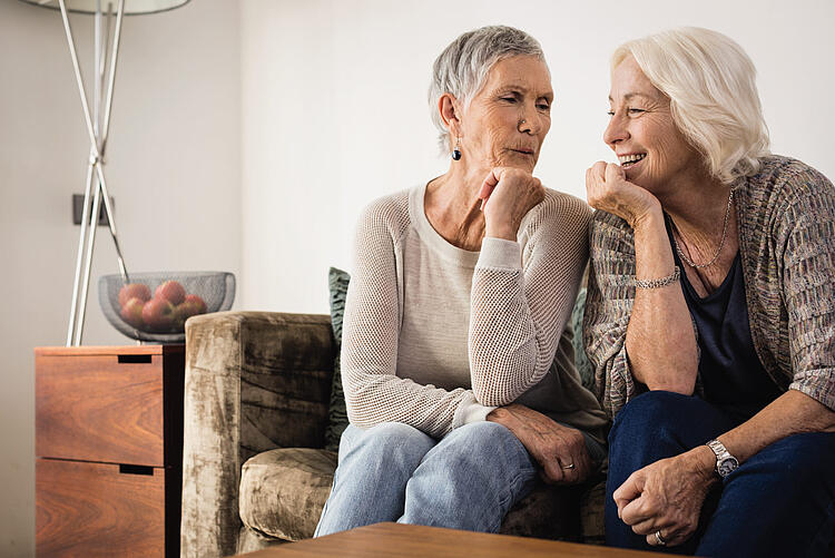 Zwei ältere Frauen sitzen zusammen auf dem Sofa und unterhalten sich