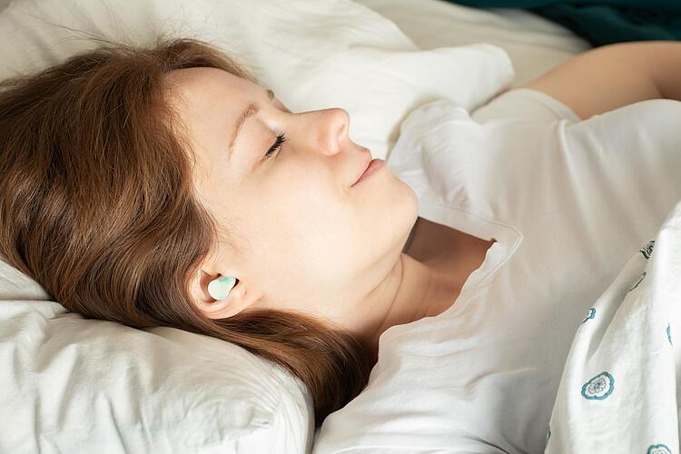 Frau schläft mit Ohrstöpseln