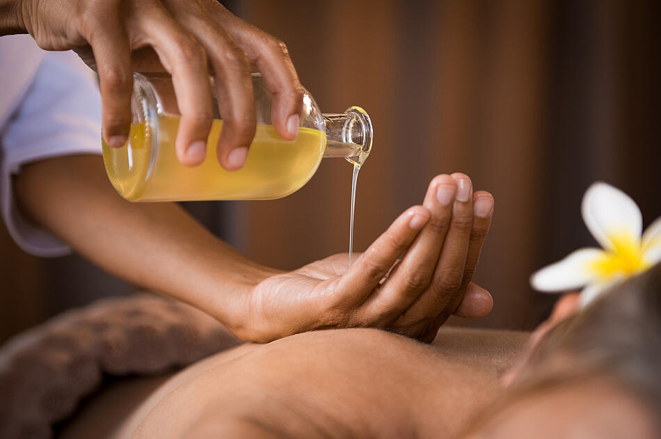 Ein Masseur gießt sich Massageöl auf die Hand.