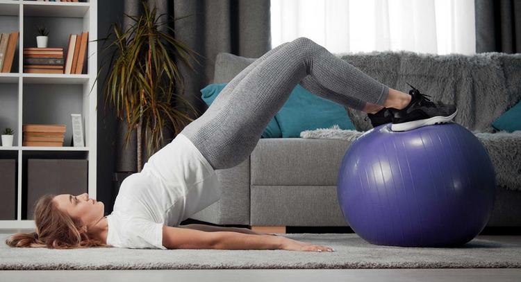 Junge Frau macht Beckenbodentraining mit einem Gymnastikball